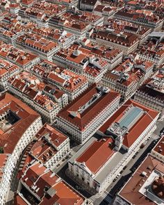 an aerial view of a city with lots of red roofs and tall buildings in the background