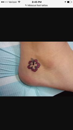 a small tattoo on the foot of a woman's leg, with a flower in the center