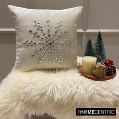 a white pillow sitting on top of a chair next to a candle and christmas tree