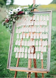 a wooden easer holding a sign with clothes on it and flowers hanging from the back