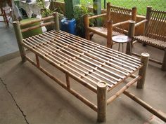 a wooden bed frame sitting on top of a cement floor next to chairs and tables