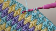 the crochet stitch is being worked on by someone using a pink crochet hook