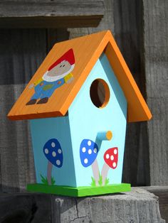 a blue birdhouse with mushrooms painted on it