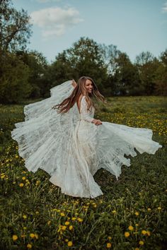 a woman in a white dress is walking through the grass with her long hair blowing in the wind