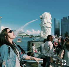 a woman standing in front of a statue with water spraying from it's mouth