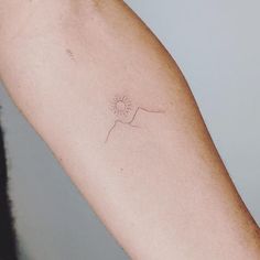 a person's arm with a small sun tattoo on the left side of their arm