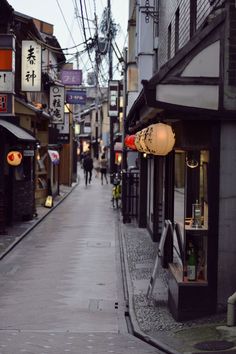 an alley way with people walking down it and shops on both sides, in the distance