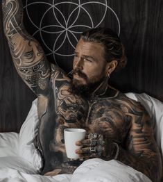 a man with tattoos holding a coffee cup