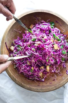 someone cutting up some food in a wooden bowl