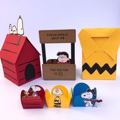 some peanuts and charlie brown paper toys are on the table next to a red house