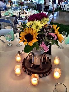 a vase filled with sunflowers sitting on top of a white table covered in candles