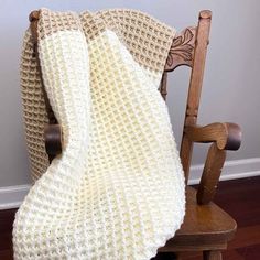 a white crocheted blanket sitting on top of a wooden chair