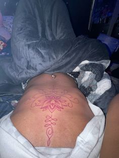 a woman laying in bed with her back turned to the camera and tattoos on her stomach