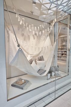 an image of a store window display with white curtains and pillows on the windowsill