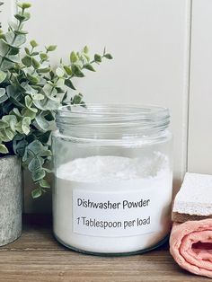 a glass jar filled with white powder next to a pink towel and potted plant