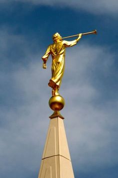 a golden statue on top of a building with a blue sky in the back ground