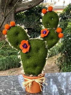 a cactus shaped plant with orange and purple flowers on it's head in a pot