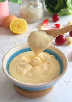 a spoon full of mayonnaise sitting in a blue and white bowl next to other ingredients