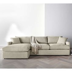 a white couch with a blanket on it in front of a wall and wooden floor