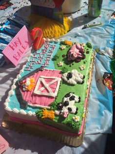 a birthday cake with farm animals on it sitting on a table next to other decorations