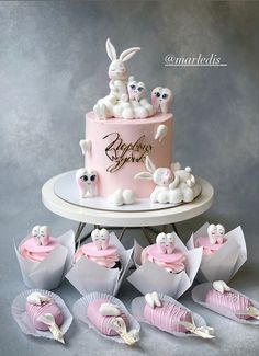 there is a pink cake with bunnies on it and bunny decorations around the cake