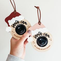 someone holding up two wooden christmas ornament tags with the words santa and snowman on them