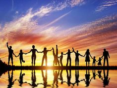 a group of people holding hands in front of a sunset