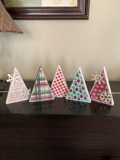 five paper christmas trees sitting on top of a wooden table next to a framed photo