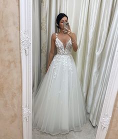 a woman taking a selfie in front of a mirror wearing a white wedding dress