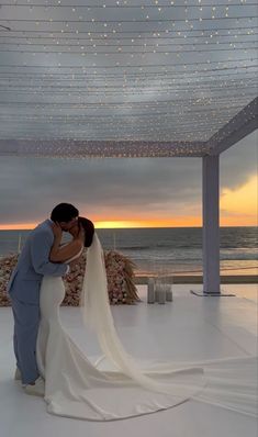 a bride and groom kissing in front of an ocean view at their wedding reception on the beach