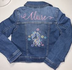 a denim jacket with embroidered unicorns and stars on the back that says e marie