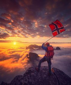 a man standing on top of a mountain holding a flag