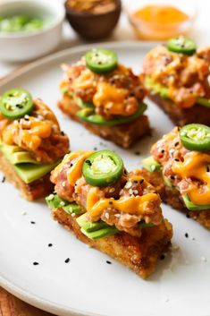 small appetizers with cheese and jalapenos are arranged on a white plate