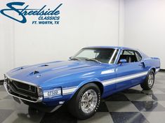 a blue muscle car sitting on top of a checkered floor