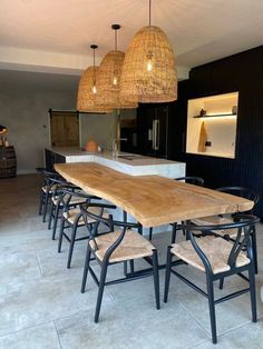 a dining room table with chairs and lights hanging from it's ceiling in front of an island