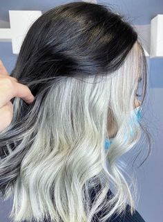 a woman with white and black hair is combing her long wavy gray haired hair