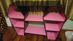 a pink and black shelving unit sitting on top of a wooden floor