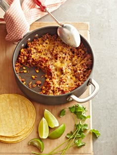 a skillet filled with mexican food next to tortillas and lime wedges