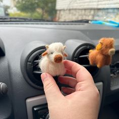 a person holding a small stuffed animal in their hand next to a car dash board