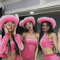 three women wearing pink outfits and hats in front of a mirror with their hands up to their face