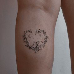 a woman's arm with a tattoo on it that has a cat in a heart surrounded by leaves