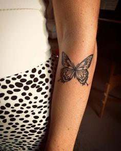 a woman's arm with a butterfly tattoo on the left side of her arm