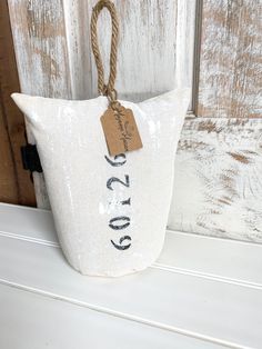 a white bag hanging on the side of a wooden door with a tag attached to it