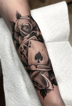 a black and white photo of a rose with playing cards on it's arm