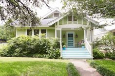 a green house with white trim and blue front door