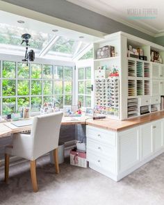 a large white desk sitting in the middle of a room filled with lots of windows