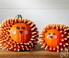 two pumpkins decorated like hedgehogs sitting on top of a wooden table next to each other