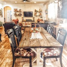 a large wooden table with chairs around it in a living room area that has wood flooring and white walls