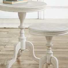 two white tables sitting on top of a hard wood floor next to a book shelf