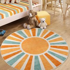 a teddy bear sitting on the floor in front of a rug with an orange and blue sun design